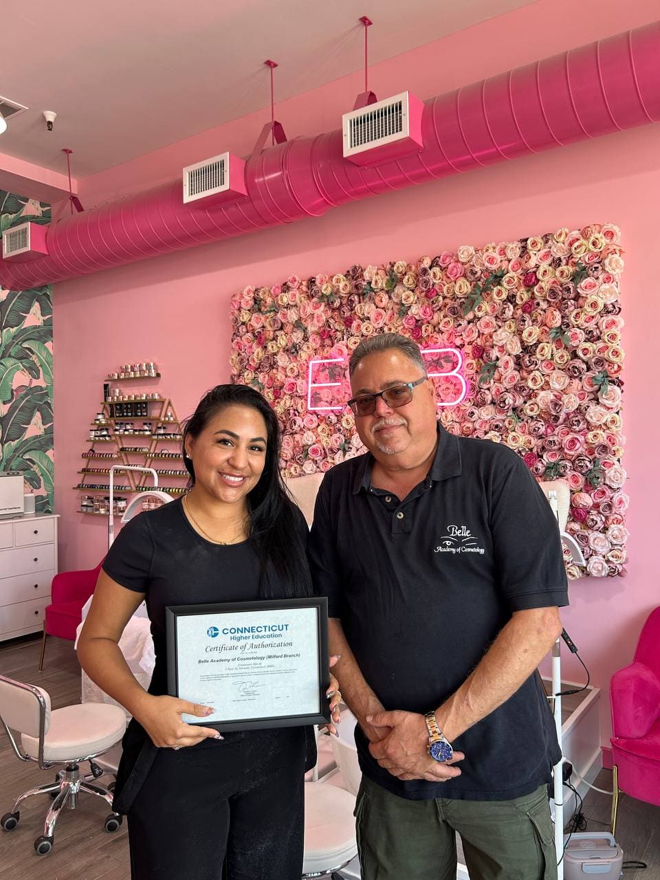 Belle Academy graduate receiving certificate at pink salon